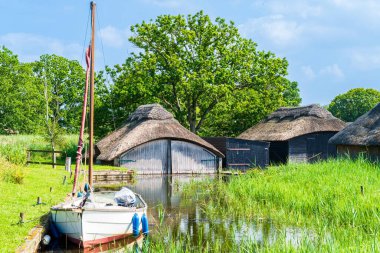 İngiltere 'deki Norfolk Broads Ulusal Parkı' ndaki Hickling Broad 'da tekne ve kayıkhaneler.