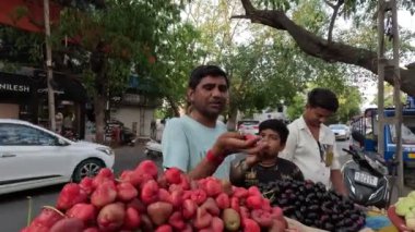 Şehirde taze liçi, kiraz ve kırmızı elma meyvesi satan bir adam var.