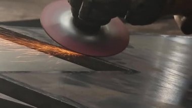 Yakın plan - fabrikanın ortasında çeliği öğütücüyle kesen adam.
