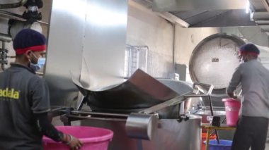 Fabrikada çalışan işçiler makine ve ekipmanlarla çalışıyorlar.