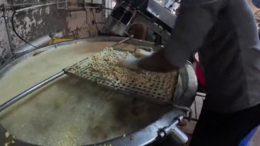 Su dolduran işçi büyük fritöz makinesine hamur doldurdu. 