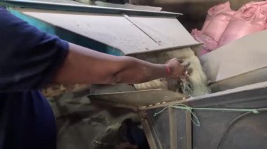 Bir adam elektrikli süpürgeyle yerleri temizliyor..
