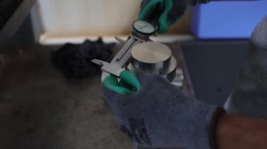 Eldivenli işçi elinde pipo tutuyor.