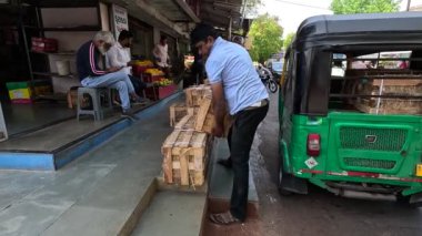 Adam mango kutularını düzenli bir şekilde dükkanın yanına yerleştiriyor.