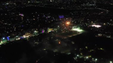 Gece gökyüzünde havai fişekler, şehrin ışıkları