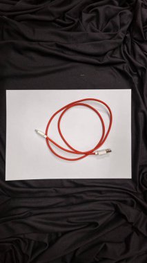 Beyaz arka planı olan beyaz bir bavkdrope üzerinde kırmızı bir kablo.