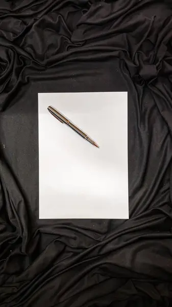 Siyah arkaplanlı siyah bir kağıt kalem, kalem ve siyah bir sayfa..