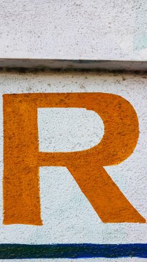 Beyaz bir duvara yazılmış R harfi.