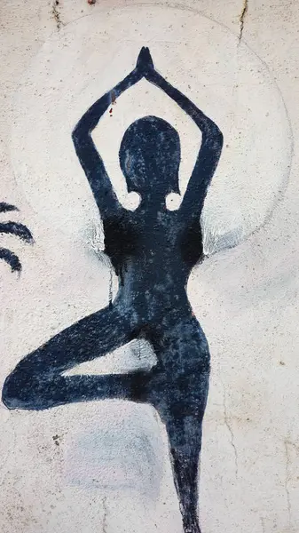 Duvarda yoga pozları veren bir kadın.