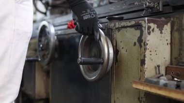 Atölyede makine üzerinde çalışan adama yaklaş.
