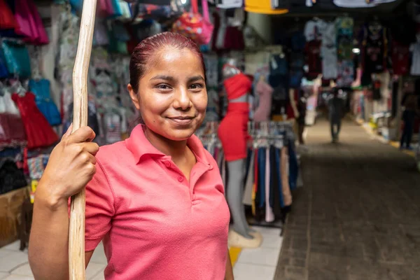 Managua, Nikaragua 'daki geleneksel bir markete giysi yerleştirmek için tahta bir sopayla giysi mağazasının önündeki perakendeciler.