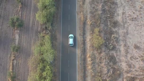 耕地近くの田舎道の車を空中撮影する 冬のメドウに近い道路に沿って飛ぶ ドローン4Kビデオ — ストック動画