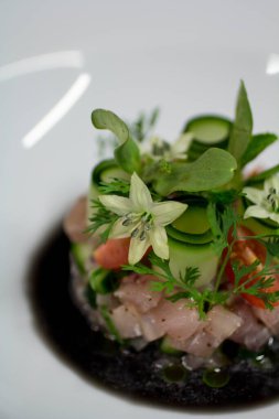 Gurme balıklı tartar ve baharatlı siyah soslu kıvrımlı lahanalar, yakın çekim..