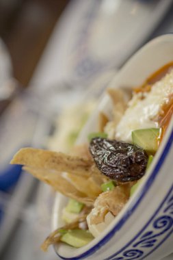 Meksika tortilla çorbası avokado, taze peynir, domuz chicharron, ve füme chipotle bir talavera kasesinde.