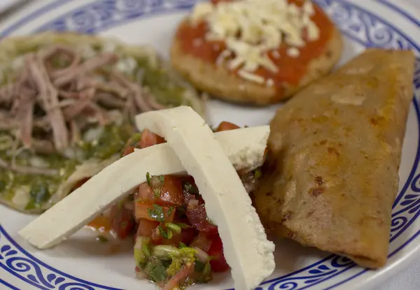 Geleneksel Meksika atıştırmalıklarının canlı çeşitleri: chalupa poblana, chipotle salsa sosu, quesadilla, ve peynirli taze pico de gallo..