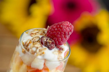 Yunan yoğurdu, ahududu ve granola soslu tropik şeftali salatası..