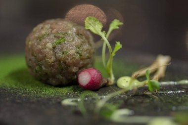 Modern çiğ ton balığı, mikro yeşillikli, kişniş soslu ve yenilebilir kişniş tozlu bir küre şeklinde, yakın plan..