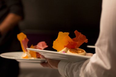 Garson, renkli ve çıtır çıtır iki tatlı taşıyor. Güzel bir yemek atmosferinde yakalandı..