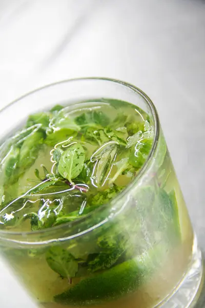 Taze naneli, limonlu ve esmer şekerli ferahlatıcı Küba mojito 'sunun dikey görüntüsü..