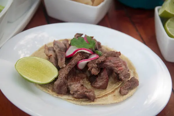 Mısırlı tortilla üzerine ızgara carne asada taco, turp, kişniş ve limon ile süslenmiş..