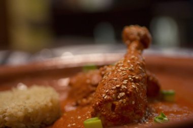 Kızarmış susam çekirdekli guajillo soslu leziz tavuklu adobo, kırsal bir tabakta poğaçalı pilav ile servis edilir..