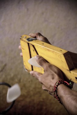 Bir sokak yemeği satıcısının, patatesi ahşap bir mandolinle dilimlerken karamsar bir ışıkta yakalandığı yakın plan..