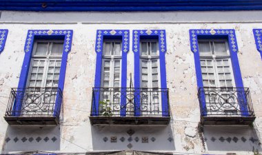 Puebla 'daki eski Meksika binası. Dört uzun mavi çerçeveli pencereli. Karmaşık Talavera fayanslarıyla süslenmiş..