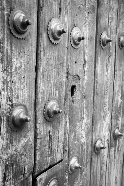 Siyah-beyaz bir Meksika Barok kapısı üzerinde yapılan çalışmalar demir çiviler ve aşınmış ahşap sömürge işçiliğini ve mimari mirasını gözler önüne seriyor..