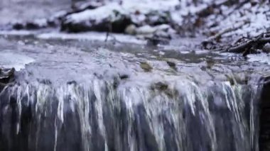 Kışın hızlı akan küçük bir nehir. Arkasında kar olan küçük bir şelale. İlkbaharda eriyen su.