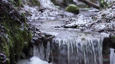 Kışın hızlı akan küçük bir nehir. Arkasında kar olan küçük bir şelale. İlkbaharda eriyen su.
