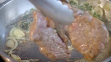 Cooking steak in cast iron pan in the kitchen at home. The cook puts butter on the steak. Steak close-up. Slow motion video. 4k ProRes footage