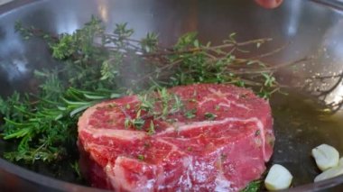 Cooking steak in cast iron pan in the kitchen at home. The cook puts butter on the steak. Steak close-up. Slow motion video. 4k ProRes footage