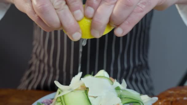 厨师把半切碎的柠檬压在一碗美味的绿色沙拉上 挤榨新鲜柠檬 — 图库视频影像