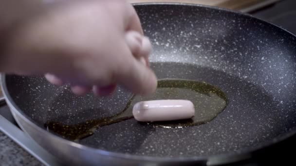一只手把香肠放在用葵花籽油包裹的热油锅里 慢镜头特写 — 图库视频影像