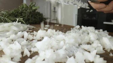 Aşçı, ahşap bir tahtanın üzerinde bir bıçakla soğan tuzluyor, doğruyor ve doğruyor. Yavaş çekim videosu. Aşçının erkek elleri. Sağlıklı yaşam tarzı, sebzeler. Soğan dilimliyorum. Seçici odak.