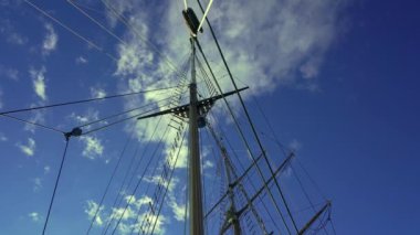 Vintage Yacht wooden mast, view up. Ropes, cables and fasteners. Blue sky. High quality 4k footage