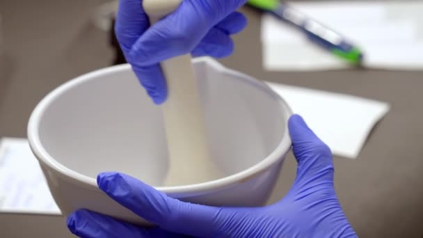 一名药剂师手拿着手套 用砂浆和沙石研磨细腻的白药混合物的合影 — 图库视频影像