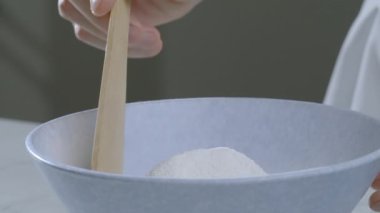 Ahşap spatulalı bir aşçı krep hamuru hazırlamak için mavi bir kâsede un karıştırır. Krep hamuru hazırlığı. Yemek hazırlığı. Yüksek kalite 4k görüntü