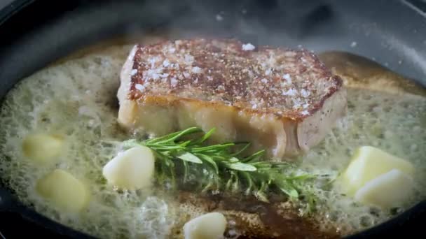 ローズマリーとニンニクの鍋にバターで揚げたステーキのジューシーなピース — ストック動画