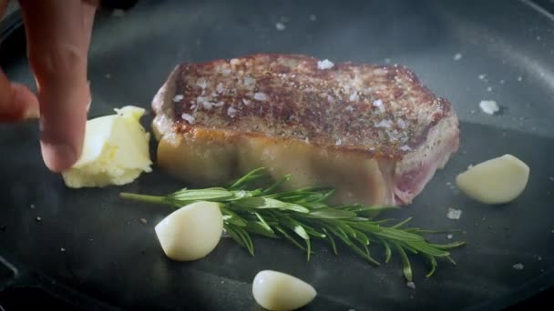 ニンニクとローズマリーの鋳鉄フライパンにステーキ 食べ物の準備 スローモーションビデオ 100Fps 高品質の4K映像を公開しました 高品質の4K映像 — ストック動画