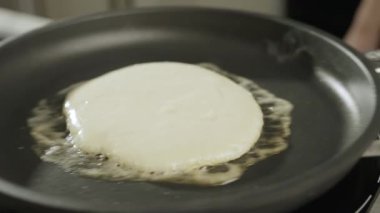 Kalın krepler pişiriyorum. Isıtılmış tavada kaygan gözleme. Mutfakta çalış. Yüksek kalite 4k görüntü