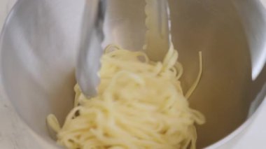 Şefin yakın plan fotoğrafı restoranın mutfağındaki metal kaseye spagetti koyuyor. Seçili odak, 4k yavaş çekim videosu. Yüksek kalite 4k görüntü