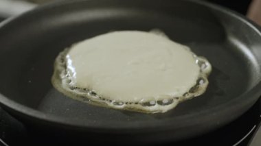 Evde krep yapıyorum. Bir Amerikan gözlemesi siyah bir tavada pişirilir. 4k Slow motion video, 100fps. Yüksek kaliteli görüntüler.