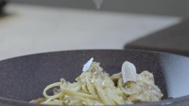 Yemek hazırlama. Siyah bir mantar dilimi spagetti makarnasının üzerine düşer. Yavaş çekim 4K video. Yüksek kalite 4k görüntü