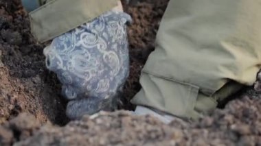 Bahar mevsimi bahçe işleri. Bahçıvanın baharda çiçek dikmek için çukur kazdığı küçük bir bahçe küreğinin yakın çekimi. Yavaş çekim 50fps 4k video.