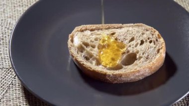 Ağır çekim. Bir dilim ekmeğin üzerine akan bal. Yüksek kaliteli FullHD görüntüler