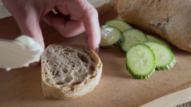 Koyu ciabatta ekmeğine ahşap bıçakla krem peynir sürüyorum. Yüksek kaliteli FullHD görüntüler