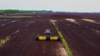 Turba çıkarma tarlaları hava görüntüsü. Bataklığın boşaltılmış alanları turba çıkartma için kullanılır. Tekerlekli traktör turbayı gevşetiyor. Yüksek kalite 4k görüntü
