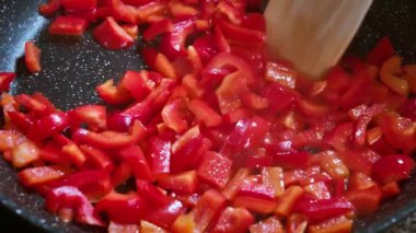 Yemek hazırlama. Kızartma tavasında doğranmış kırmızı dolma biber. Kızartma tavasında sebze kızartmak. Sağlıklı taze sebzeler. Sağlıklı vejetaryen yemekleri pişirmek.. 