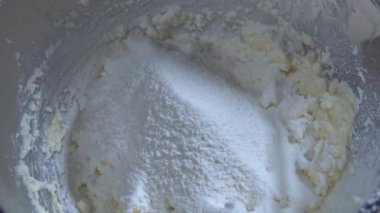 Aşçı, tatlı kurabiye hamuru için malzemelerle karıştırılmış un ekler. Un ekleniyor.
